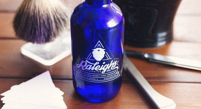 Clear beard oil sticker applied to blue glass bottle