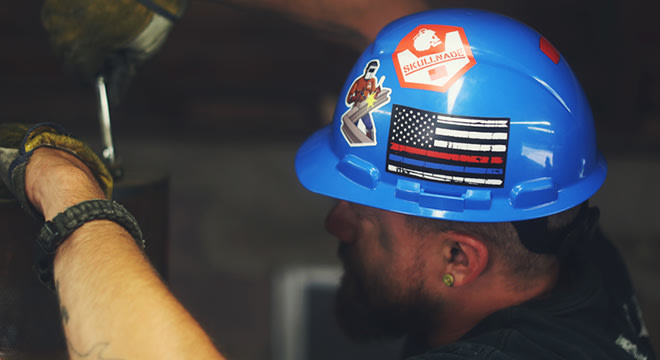 Construction worker wearing a blue hard hat with stickers