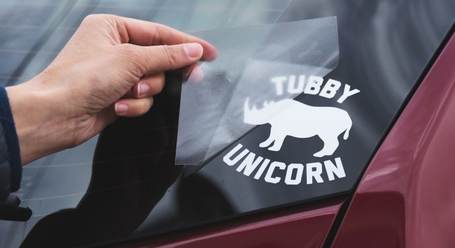 Applying a decal of a tubby unicorn to a rear window of a car