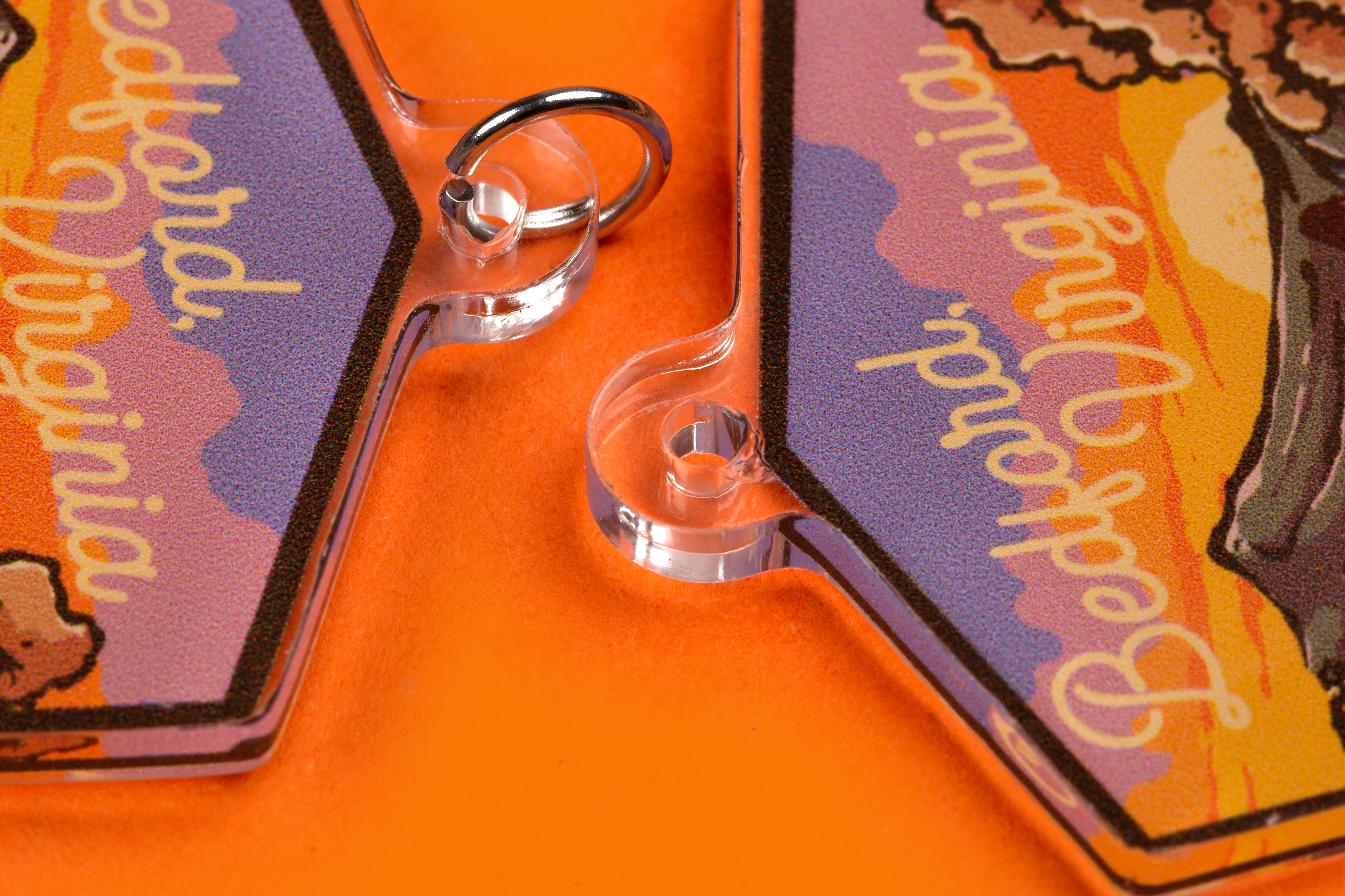 close up of a custom acrylic charm cut hole on an orange background