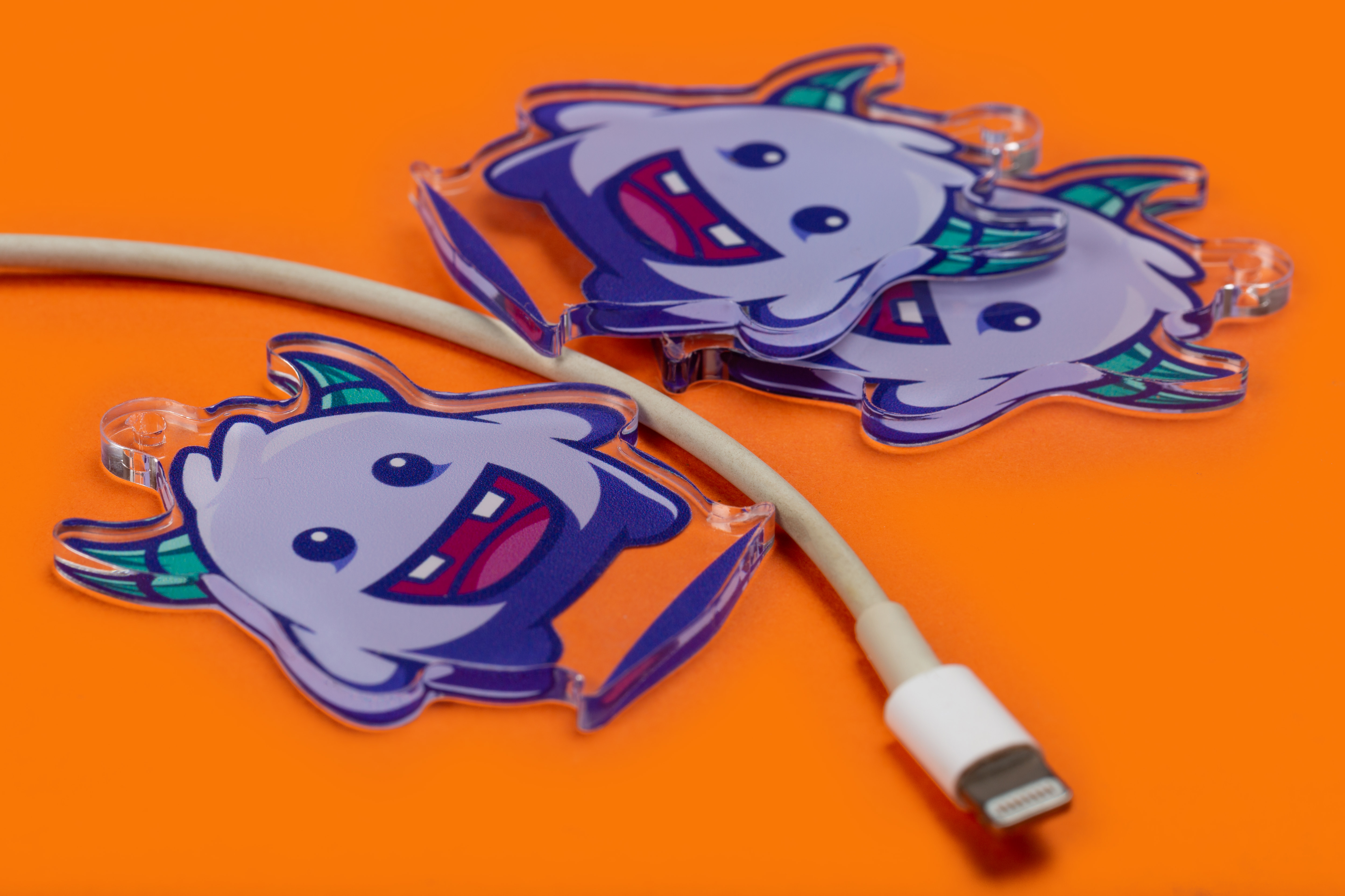 dijes acrílicos personalizados junto a un cable de carga de iphone