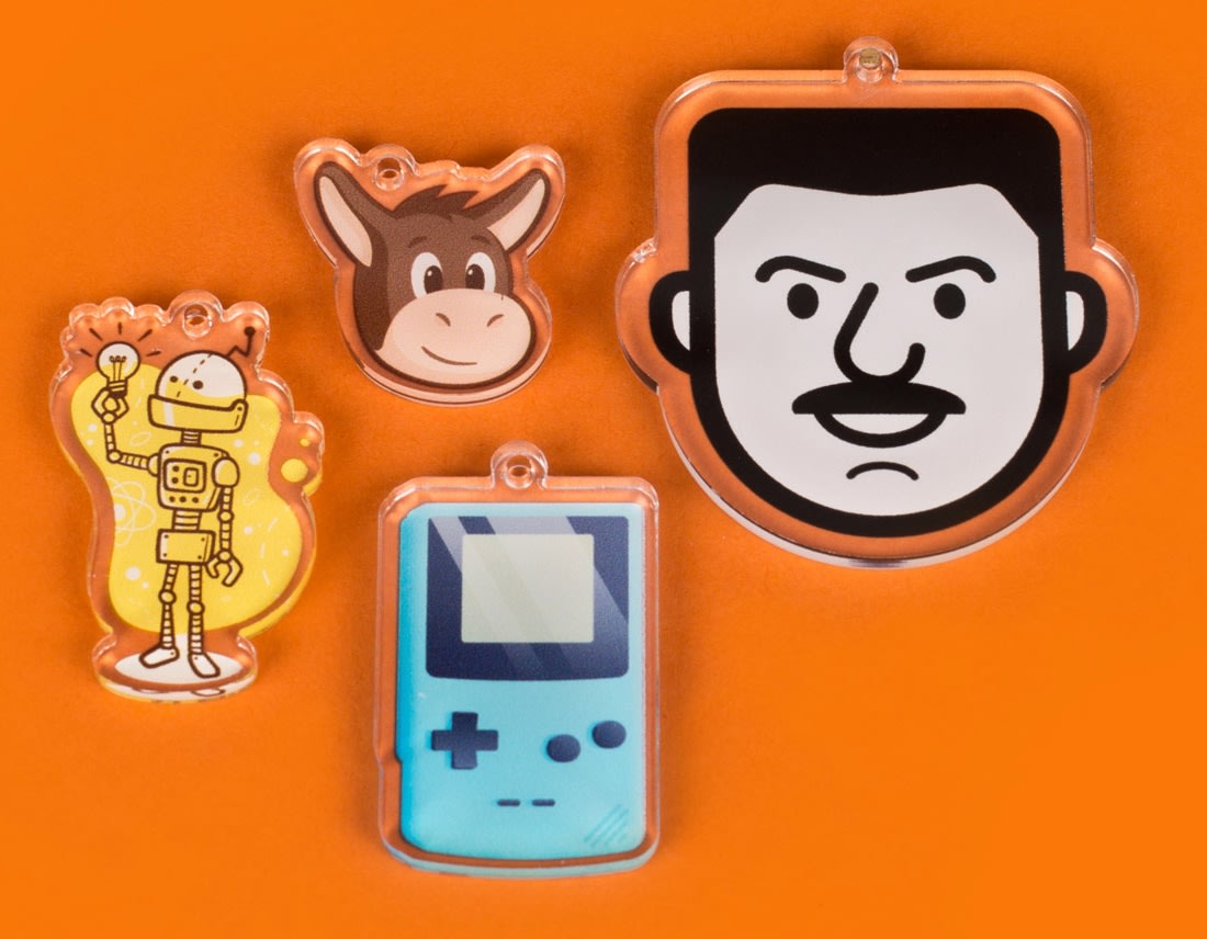 various clear printed custom acrylic charms of faces figures and portable gaming device