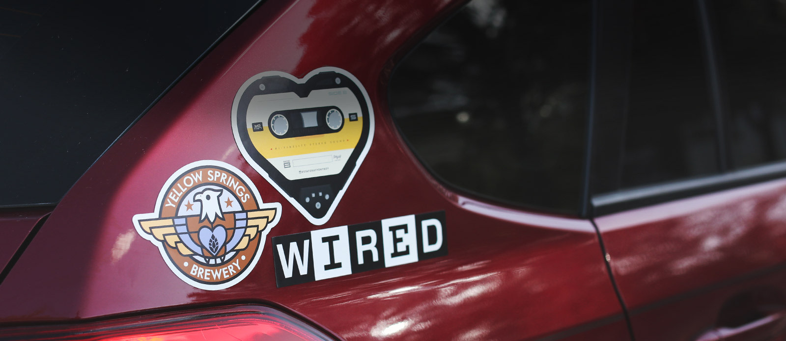 três imas personalizados em um carro vermelho