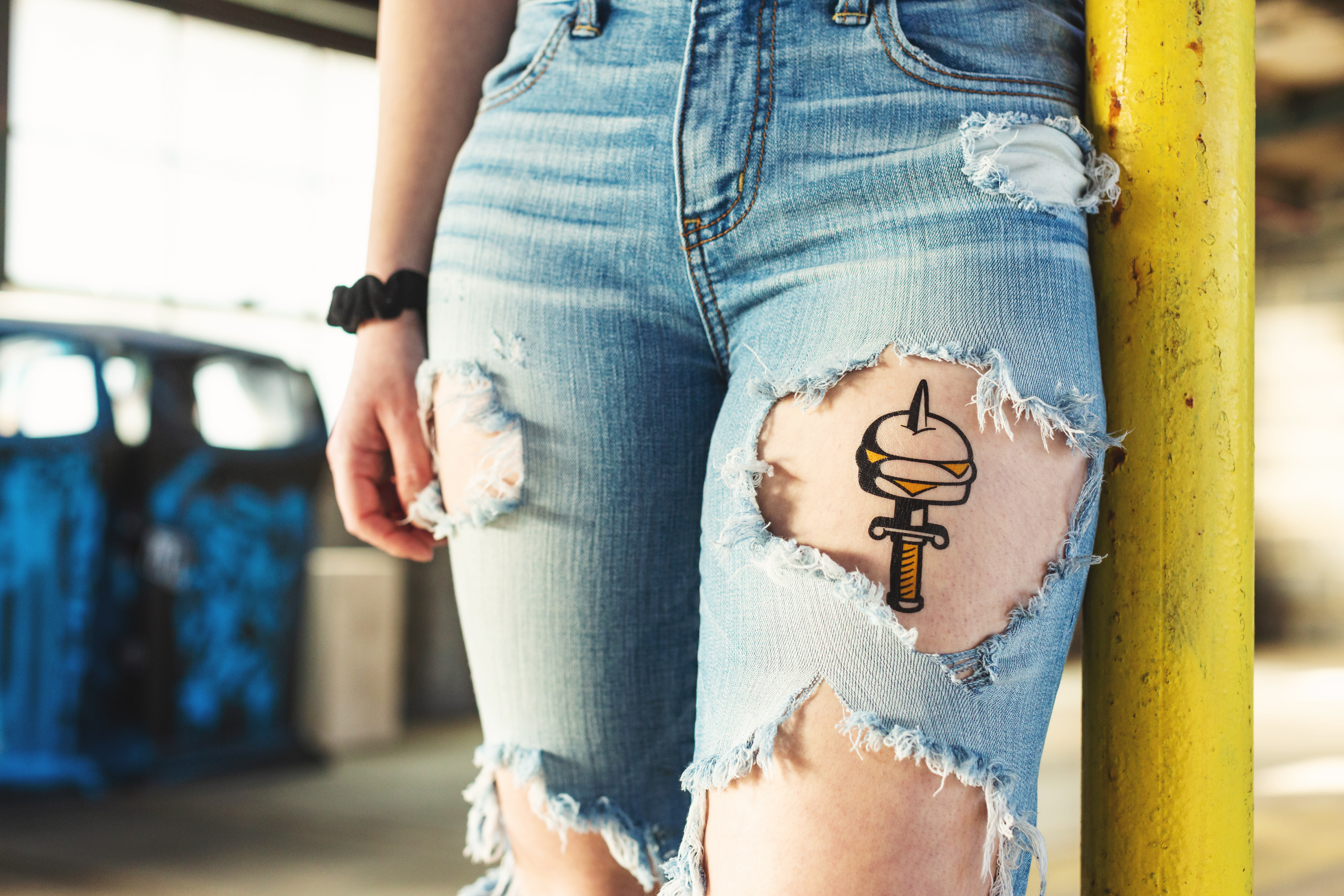 Frau trägt Jeans mit Löchern und individuellen temporären Tattoos