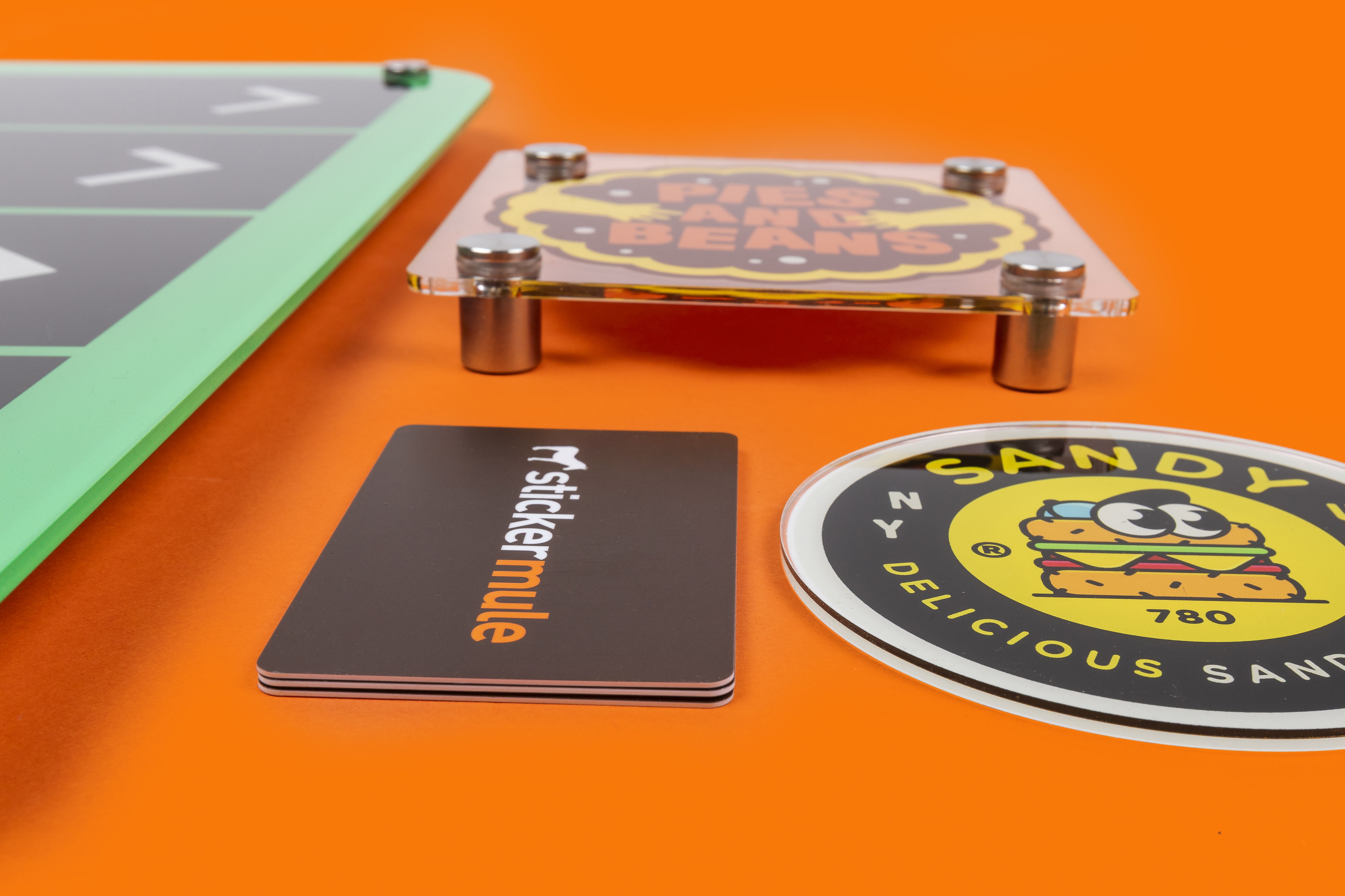 Image of an acrylic sign with three sticker mule gift cards stacked next to it for thickness reference. 