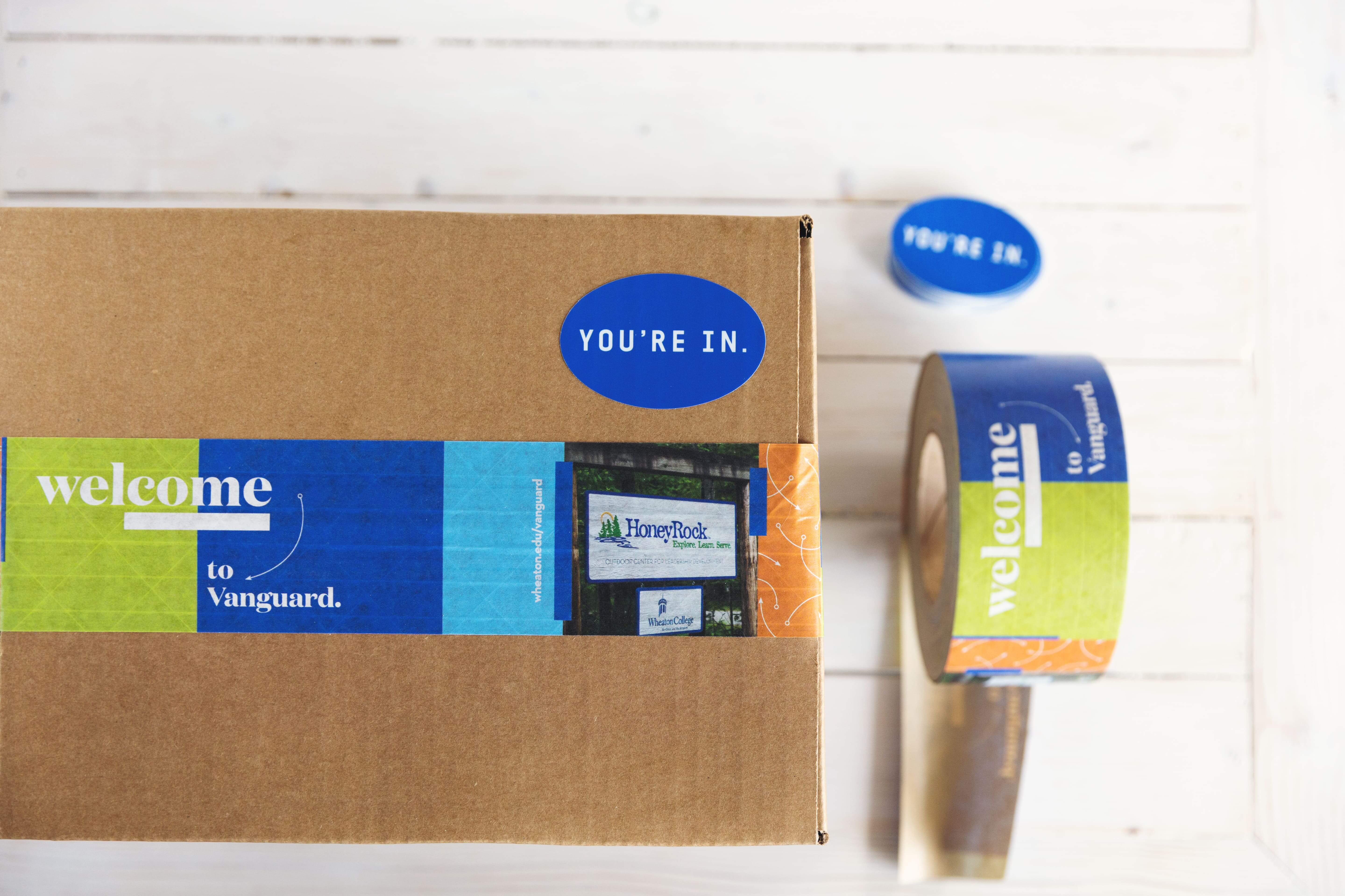 Una caja de envío con un sticker azul ‘You’re in’ aplicado a ella.