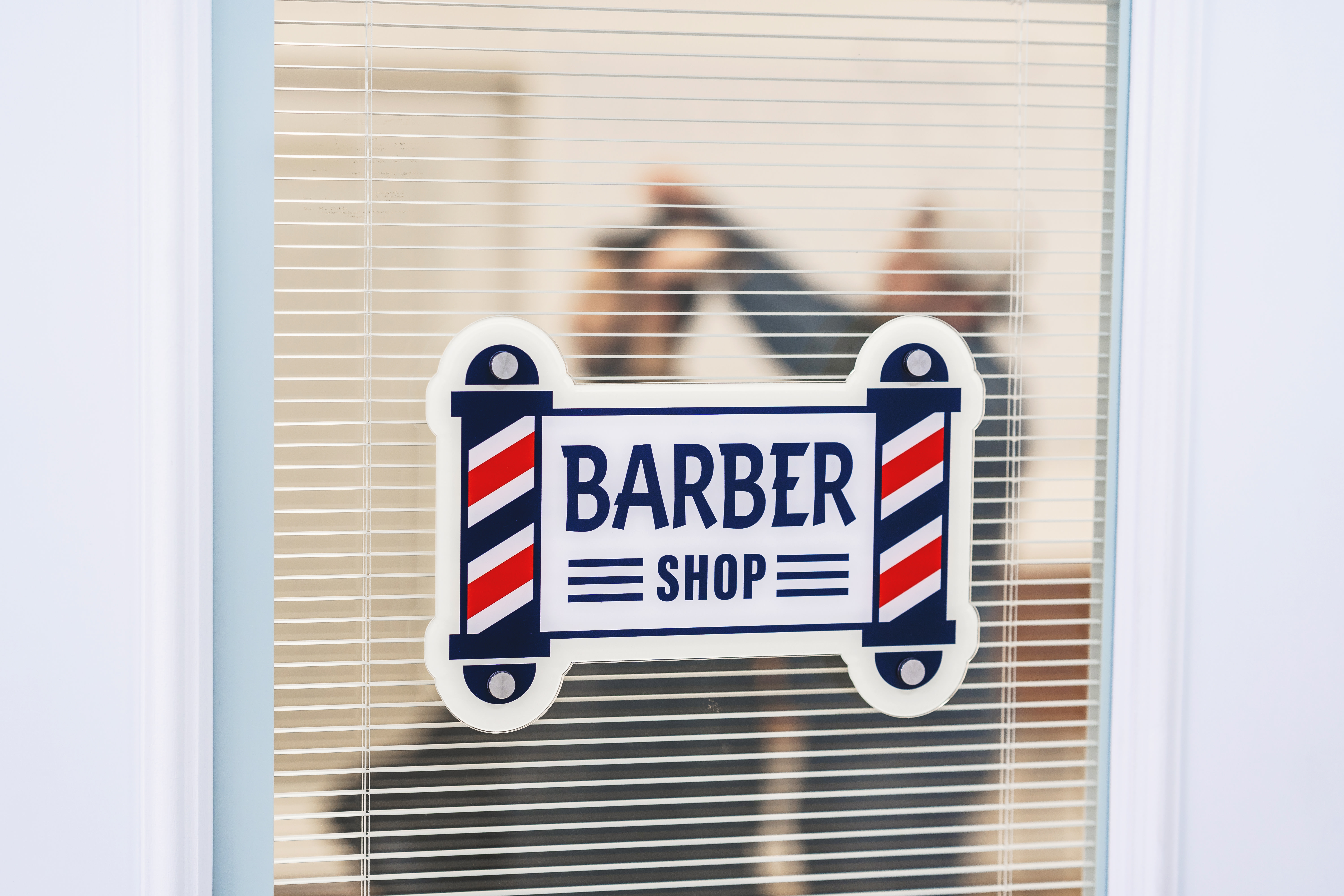 placa de acrílico recortada com a frase "barber shop" cortada na forma de dois postes de barbearia